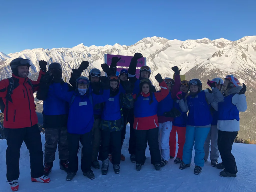 Gruppe jubelt auf dem Berg vor dem Panorama.